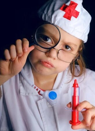 虫眼鏡とおもちゃの注射器を手に持ち、真剣なまなざしで診察する小さい子供
